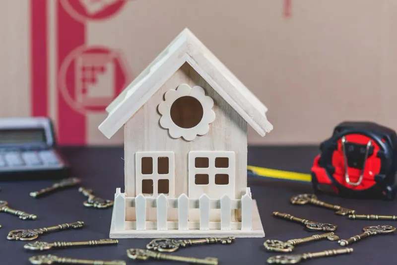 Small wooden model house surrounded by keys on a table