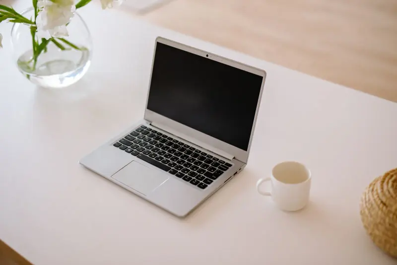 Open laptop and a coffee cup on a bright white desk